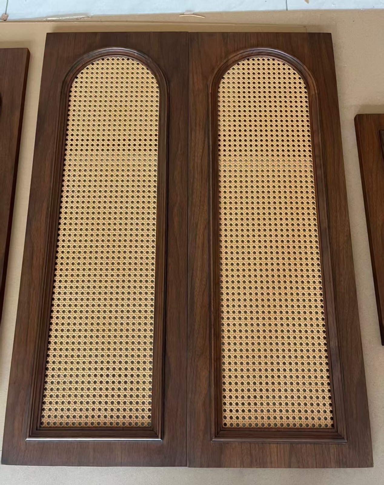 Paired black walnut arched cabinet doors with woven cane inserts.