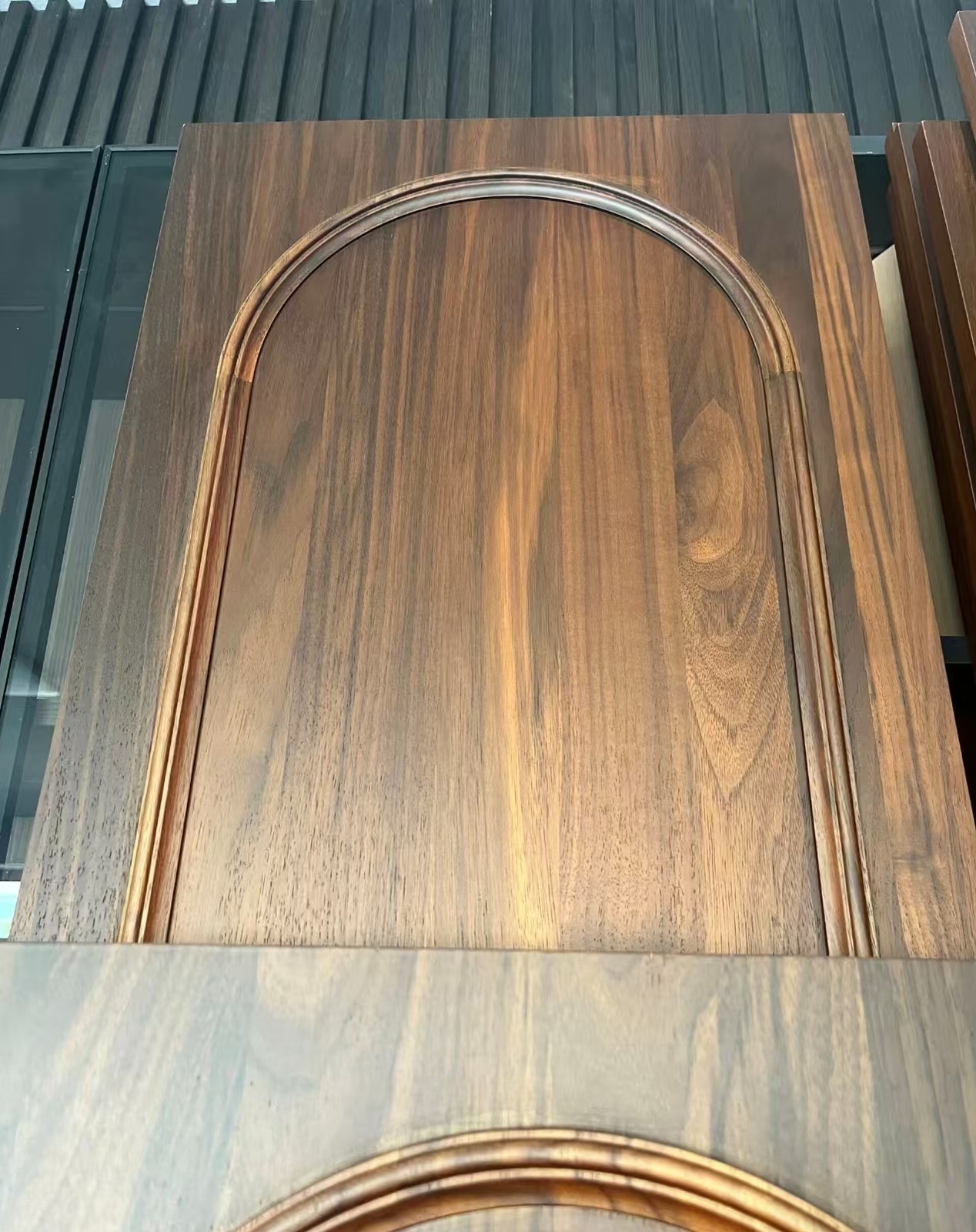 Close view of black walnut cabinet-door grain and arched moulding detail.