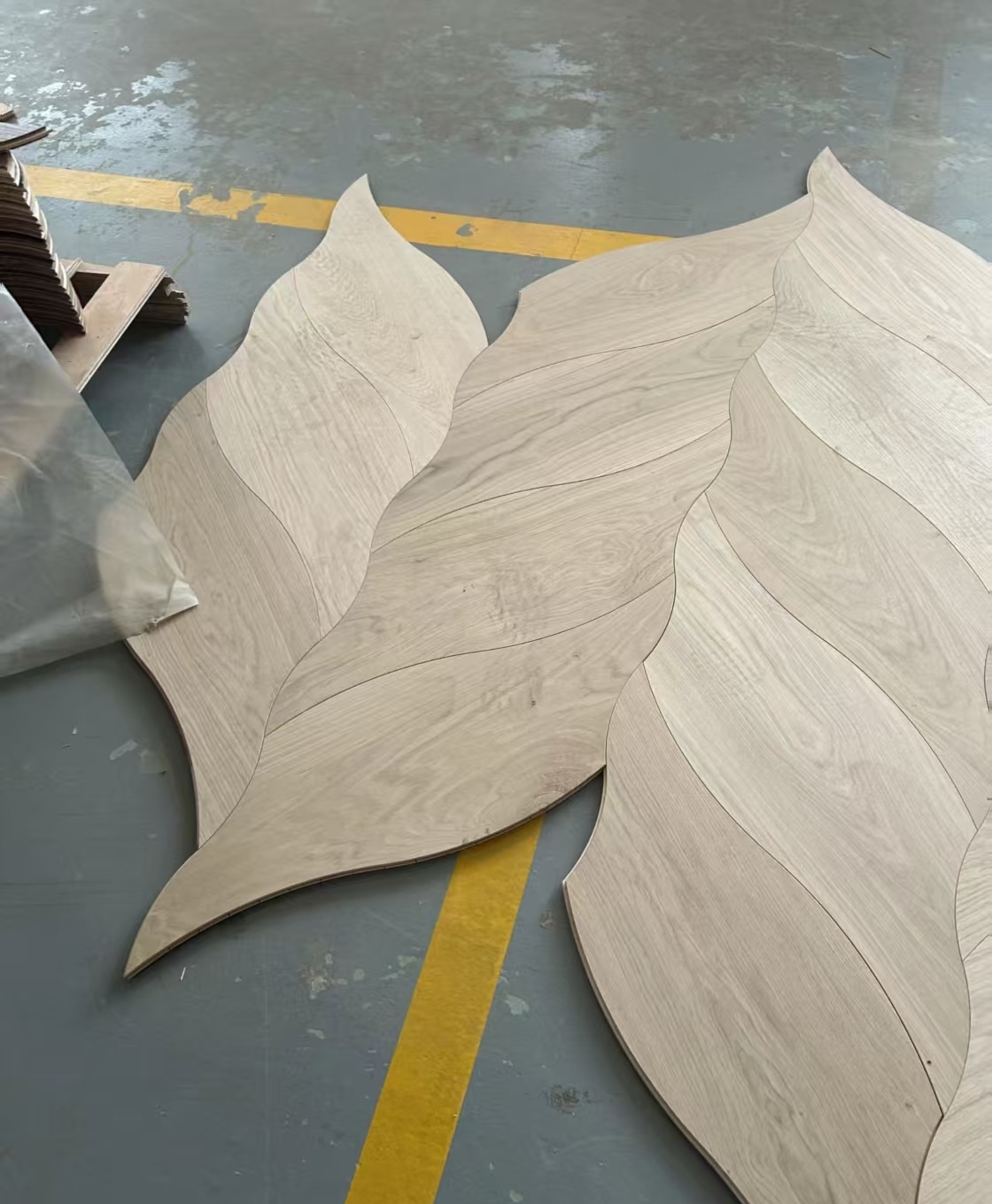 Several shaped veneer pieces arranged on a workshop floor with flowing curved joins.