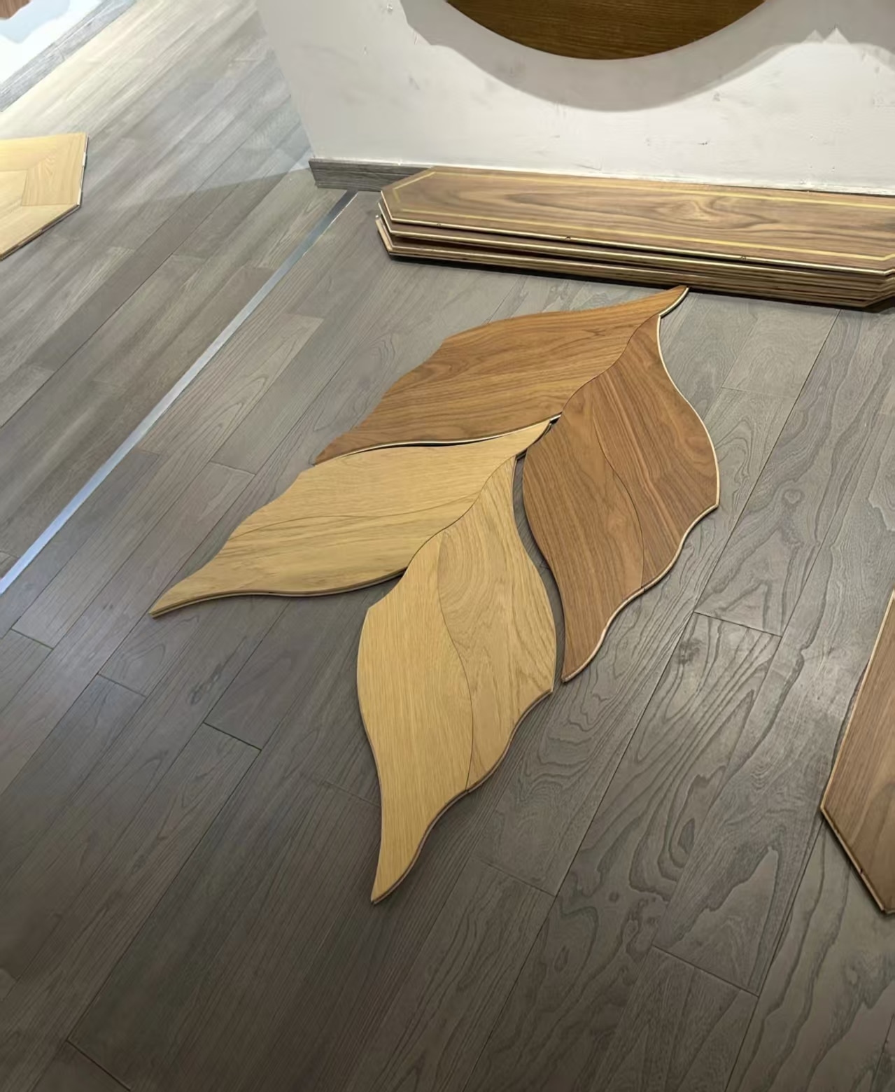 Leaf-shaped wood pieces in contrasting tones arranged on a floor.