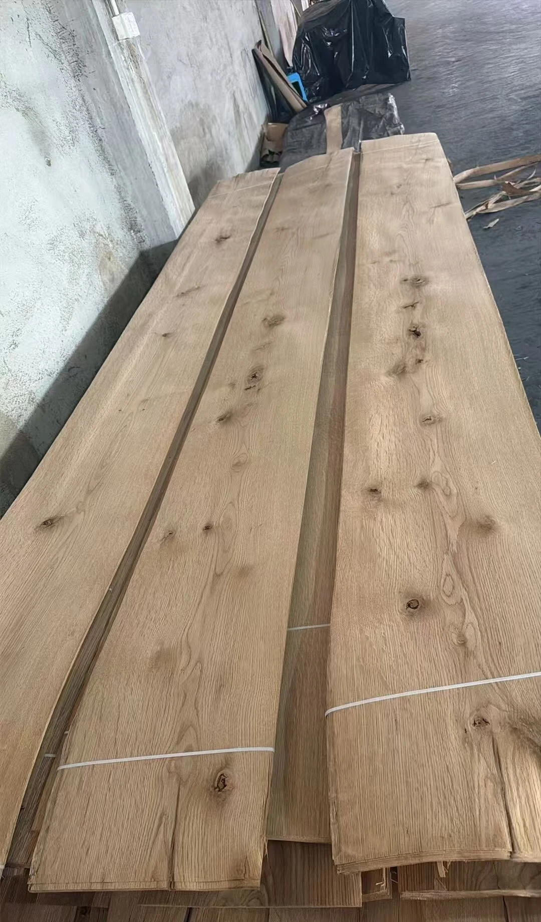 Raw veneer leaves showing natural knots, oak grain and bundle straps.